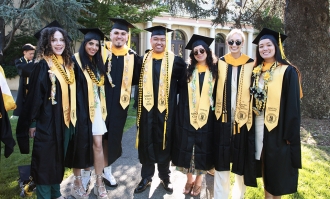 A group of graduates wearing caps and gowns and smiling.